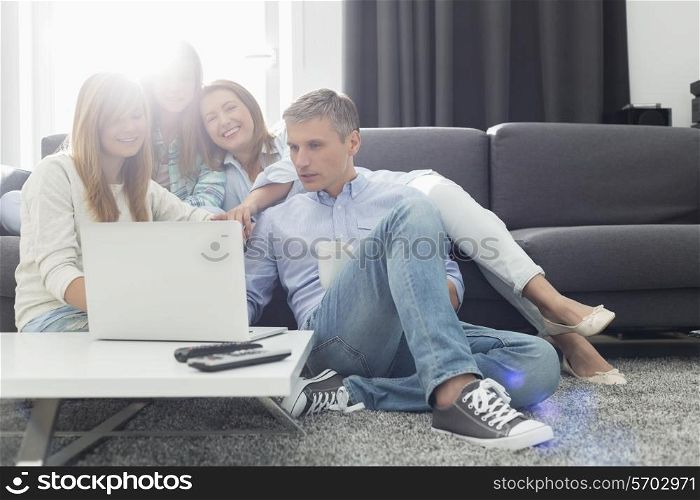 Happy parents with daughters using laptop in living room