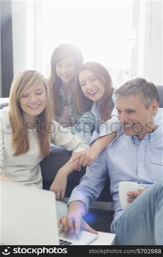 Happy parents with daughters using laptop in living room