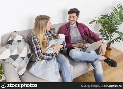 happy parents with sleeping baby using laptop