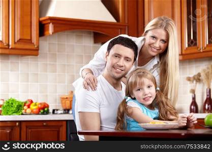 Happy parents with the child on kitchen