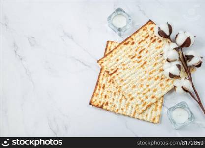 Happy Passover concept. Matzo bread and cotton flowers on white marble. Background religious Jewish holiday Pesach. Copy space.. Happy Passover concept. Matzo bread and cotton flowers on a white marble. Background religious Jewish holiday Pesach. Copy space.