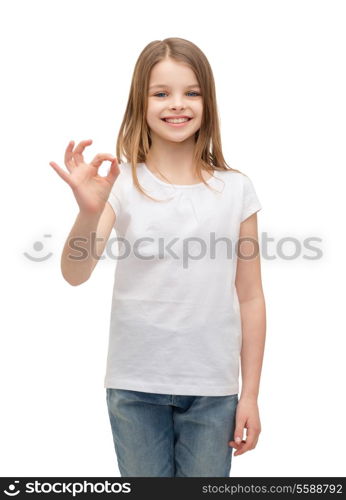 happy people and gesture concept - smiling little girl in blank white t-shirt showing ok gesture