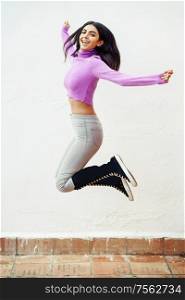Happy Persian woman jumping outdoors on white wall background. Happy persian woman jumping outdoors on white wall