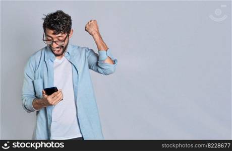 Happy person holding a smartphone and celebrating isolated, Excited man winning a prize from his cellphone. Excited handsome man looking at smartphone celebrating something