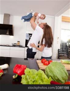 Happy playful family in kitchen - father mother and toddler son