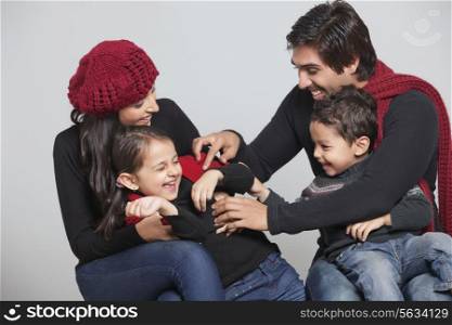 Happy playful family sitting over grey background