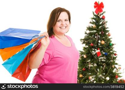 Happy plus sized model holding shopping bags, standing in front of a Christmas tree. Isolated on white.
