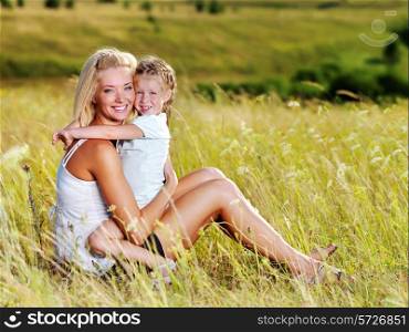 Happy portrait of the mother and little daughter on meadow
