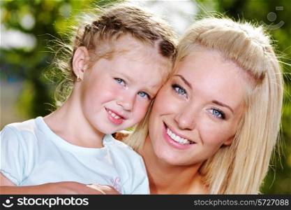 Happy portrait of young mother and cute little daughter - on the nature