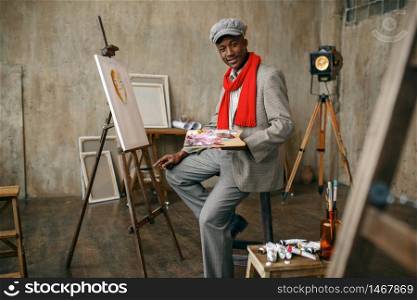 Happy portrait painter with brush draws female model in art studio. Male artist at his workplace, creative master at the easel in workshop. Happy painter draws female model in art studio