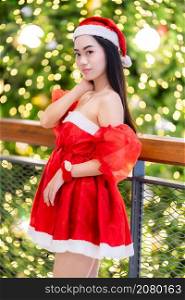 happy portrait young asian woman Santa costume and Christmas greeting picture parcel decoration on Christmas tree light Abstract circular bokeh background Decoration During Christmas and New Year.