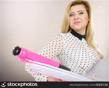 Happy positive accountant business woman holding pink binder with documents and big pen, enjoying her work, on grey. Happy positive business woman holding binder with documents