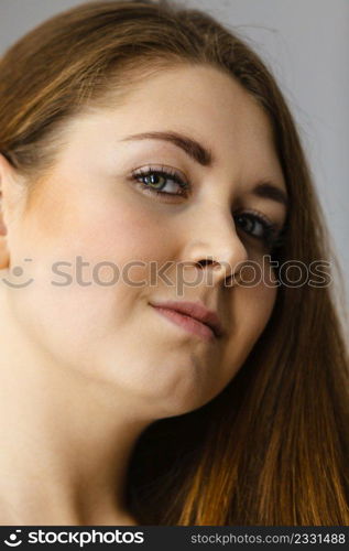 Happy positive woman with long brown hair presenting her healthy hairdo. Haircare concept. Studio shot on grey backgorund.. Happy positive woman with long brown hair