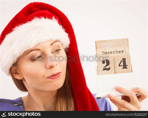Happy positive young teenage woman wearing Santa Claus christmas hat holding calendar with 24 december date.. Happy woman holding 24 december date