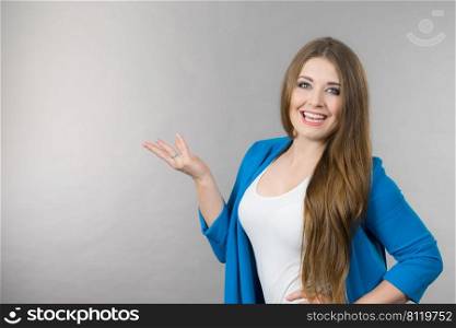 Happy positive young woman being elegant wearing blue stylish jacket gesturing with hands at copy space.. Elegant woman gesturing with hands