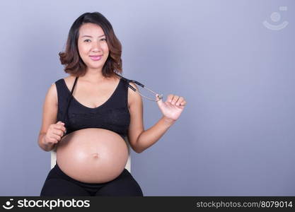 happy pregnant asian woman with stethoscope