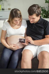 Happy pregnant couple looking on ultrasound baby scan