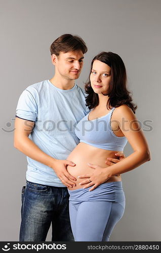 Happy pregnant couple over grey background