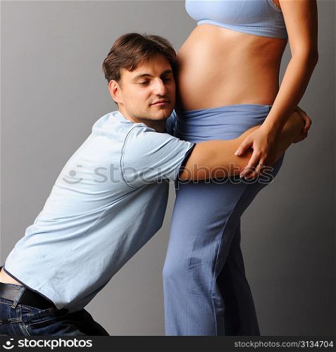 Happy pregnant couple over grey background