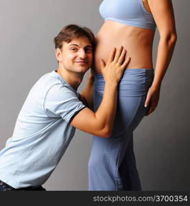 Happy pregnant couple over grey background