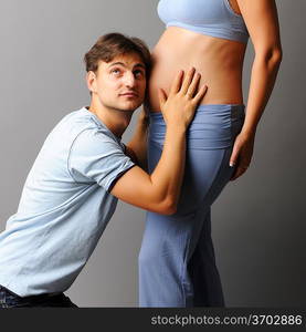 Happy pregnant couple over grey background