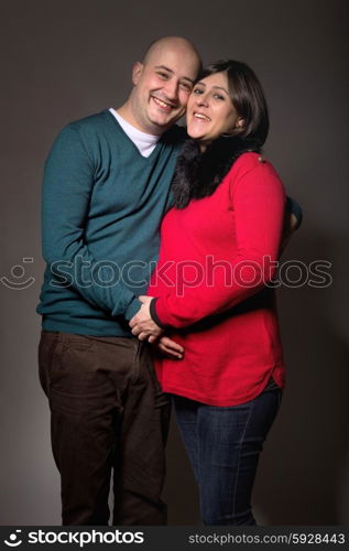 happy pregnant couple posing on dark background