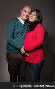 happy pregnant couple posing on dark background