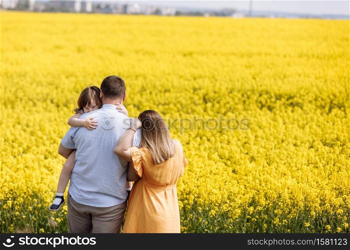 Happy pregnant family with little daughter spending time together in a yellow rapeseed field on summer day. selective focus.. Happy pregnant family with little daughter spending time together in a yellow rapeseed field on summer day. selective focus