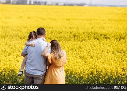 Happy pregnant family with little daughter spending time together in a yellow rapeseed field on summer day. selective focus.. Happy pregnant family with little daughter spending time together in a yellow rapeseed field on summer day. selective focus