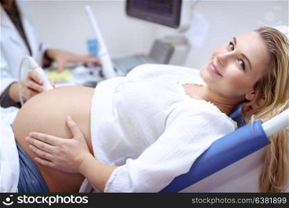 Happy pregnant female visiting women&rsquo;s doctor in the maternity center, with pleasure doing ultrasound scan, checking health of the child, healthy motherhood concept