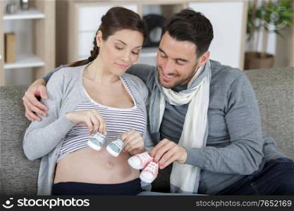 happy pregnant parents holding colorful baby boots