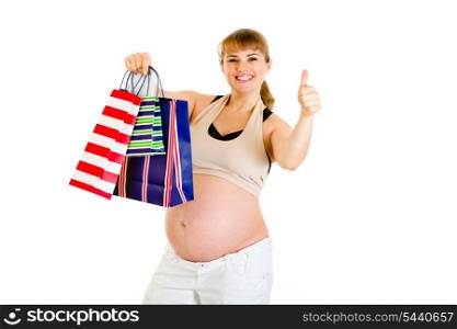 Happy pregnant woman holding shopping bags and showing thumbs up gesture isolated on white&#xA;