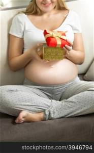 Happy pregnant woman looking inside of gift box