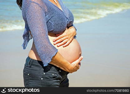 Happy pregnant woman on the beach at the atlantic ocean