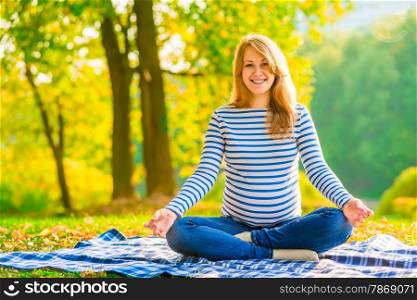 happy pregnant woman relaxing on the lawn in the park