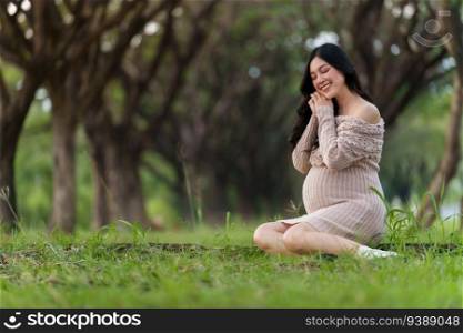 happy pregnant woman sitting in the park