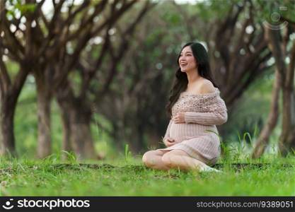 happy pregnant woman sitting in the park