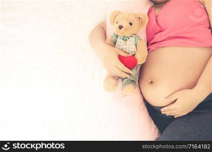 Happy pregnant woman sleeping on bed in bedroom at home for resting and stress relief. The young expecting mother holding baby in pregnant belly. Maternity prenatal care and woman pregnancy concept.. Happy pregnant woman sleeping on bed in bedroom.