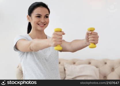 happy pregnant woman using yellow weights