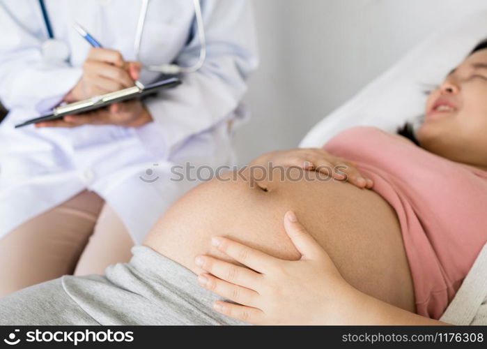 Happy pregnant woman visit gynecologist doctor at hospital or medical clinic for pregnancy consultant. Doctor examine pregnant belly for baby and mother healthcare check up. Gynecology concept.. Pregnant Woman and Gynecologist Doctor at Hospital