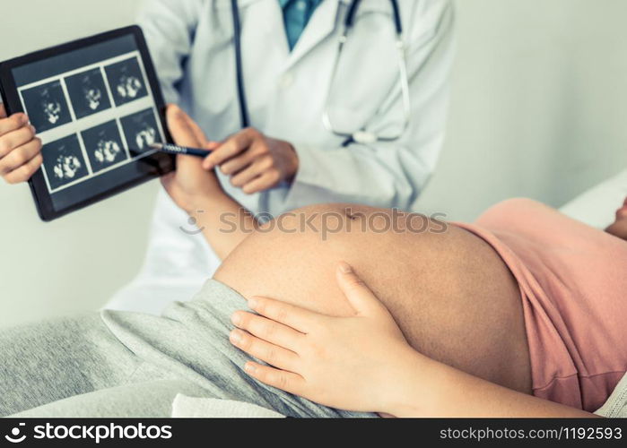 Happy pregnant woman visit gynecologist doctor at hospital or medical clinic for pregnancy consultant. Doctor examine pregnant belly for baby and mother healthcare check up. Gynecology concept.. Pregnant Woman and Gynecologist Doctor at Hospital