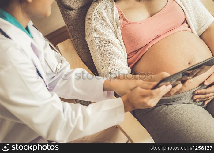 Happy pregnant woman visit gynecologist doctor at hospital or medical clinic for pregnancy consultant. Doctor examine pregnant belly for baby and mother healthcare check up. Gynecology concept.. Pregnant Woman and Gynecologist Doctor at Hospital