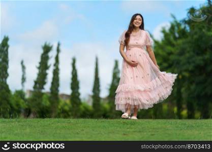 happy pregnant woman walking in the park