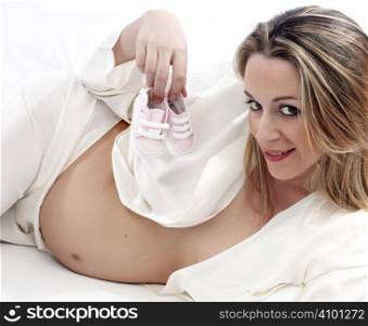 happy pregnant woman with baby shoes