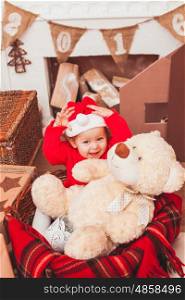 Happy pretty baby dressed in costume Santa Claus with Christmas gifts. Festive Christmas decoration
