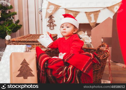 Happy pretty baby dressed in costume Santa Claus with Christmas gifts. Festive Christmas decoration