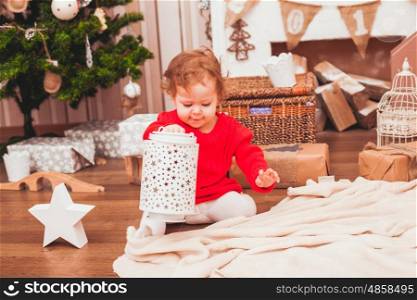 Happy pretty baby dressed in red dress with Christmas gifts. Festive Christmas decoration