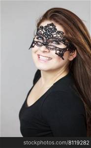 Happy pretty mysterious woman wearing black eye lace mask having long brown hair.. Mysterious woman wearing lace mask