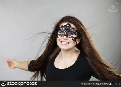 Happy pretty mysterious woman wearing black eye lace mask having tousled windblown long brown hair.. Mysterious woman wearing lace mask
