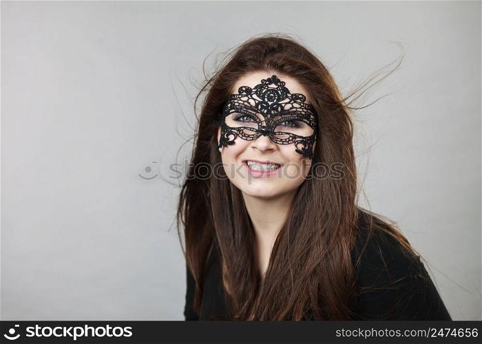 Happy pretty mysterious woman wearing black eye lace mask having tousled windblown long brown hair.. Mysterious woman wearing lace mask